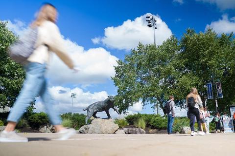 Students walking in a blur past the UNH Wildcat statue